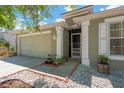 Inviting entrance featuring a screen door, brick-lined flower beds, and painted columns at 7705 Dragon Fly Loop, Gibsonton, FL 33534