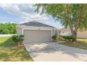 Charming single-story home with a two-car garage and a well-maintained lawn with mature shade trees at 7939 Merchantville Cir, Zephyrhills, FL 33540