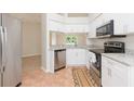 Modern kitchen with white cabinets, stainless steel appliances, and granite countertops is adjacent to the living area at 7939 Merchantville Cir, Zephyrhills, FL 33540
