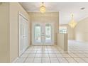 Welcoming foyer with decorative glass double doors, high ceilings, tile flooring, and elegant chandeliers at 9395 Belvedere St, Spring Hill, FL 34608