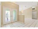 Inviting foyer featuring decorative glass double doors, tile flooring, and elegant chandelier at 9395 Belvedere St, Spring Hill, FL 34608