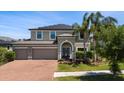 Two-story home with a three-car garage, brick driveway, and well-manicured lawn and landscaping at 10712 Pleasant Knoll Dr, Tampa, FL 33647