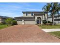 Inviting two-story home featuring a three-car garage, brick driveway, and beautifully landscaped yard at 10712 Pleasant Knoll Dr, Tampa, FL 33647