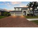 Charming home featuring a three-car garage, a brick driveway, and lush landscaping at 10712 Pleasant Knoll Dr, Tampa, FL 33647