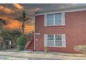 Close-up of a red brick condo showcasing white trim, a private entrance, stairs, and tropical foliage at 1095 82Nd N Ter # 1095A, St Petersburg, FL 33702