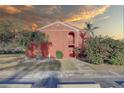 Exterior view of a red brick two-story condo featuring tropical plants, a private entrance, a small balcony, and a beautiful sky at 1095 82Nd N Ter # 1095A, St Petersburg, FL 33702