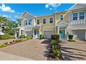 Charming multi-story townhomes featuring colorful exteriors, attached garages, and a welcoming paver driveway at 1103 Coral Ln, Dunedin, FL 34698