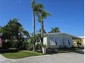 Quaint one-story home with shuttered windows and a covered carport, surrounded by mature trees and greenery at 121 Dolphin S Dr, Oldsmar, FL 34677