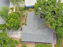 Aerial view of a gray shingle roof surrounded by mature trees and lush greenery at 1320 Whispering Pines Dr, Clearwater, FL 33764