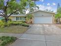 Well-maintained single-Gathering home with a two-car garage, manicured lawn, and stone accents at 1320 Whispering Pines Dr, Clearwater, FL 33764