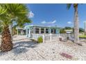 Charming light blue home features a white picket fence and outdoor seating area, perfect for enjoying the beautiful surroundings at 13200 Boca Ciega Ave, Madeira Beach, FL 33708