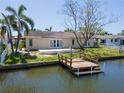 Canal-front home featuring private dock, manicured lawn, and outdoor living space at 1419 47Th Ne Ave, St Petersburg, FL 33703