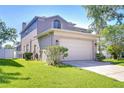 Exterior shot of home with two car garage, lush lawn, and a fenced in backyard at 1632 Gray Bark Dr, Oldsmar, FL 34677