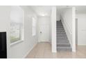 Bright foyer with neutral tile flooring, staircase, and front door with sidelight and large windows at 20224 Pond Apple Ln, Tampa, FL 33647