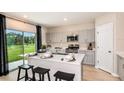 Open kitchen with stainless steel appliances, grey cabinets, a large island and a large window at 37213 Sagemoor Dr, Zephyrhills, FL 33541