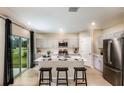 Modern kitchen with gray cabinets, stainless steel appliances, island with seating, and sliding door to back yard at 37230 Sagemoor Dr, Zephyrhills, FL 33541