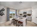 Open concept kitchen with gray cabinets, a center island with seating, and a sliding glass door with lake views at 37252 Sagemoor Dr, Zephyrhills, FL 33541