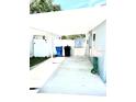 Long carport with a concrete floor extending to a backyard area with access to a shed at 3318 Boca Ciega N Dr, St Petersburg, FL 33710