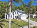 Attractive two-story home surrounded by palm trees, featuring a well-kept lawn and a two-car garage at 389 Waterford W Cir, Tarpon Springs, FL 34688
