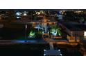 Nighttime view of a waterfront home featuring a private dock, elevated deck, and landscape lighting at 4290 Carlos Ct, Hernando Beach, FL 34607