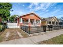 Charming single-story home featuring an orange facade, black metal fence, and quaint front porch at 6414 N Central Ave, Tampa, FL 33604