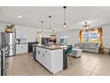 Open-concept kitchen and living room with island, stainless steel appliances, and comfortable sectional couch at 10937 Penny Gale Loop, San Antonio, FL 33576