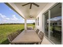 Covered patio with outdoor dining table and chairs overlooking a spacious green lawn and beautiful blue sky at 12166 Cattleside Dr, Riverview, FL 33579