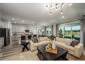 Open-concept living room and kitchen with modern light fixtures, stainless steel appliances, and hardwood flooring at 12168 Cattleside Dr, Riverview, FL 33579
