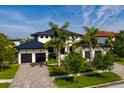 Beautiful two-story home with a black metal roof, white stucco, three-car garage and mature palm tree landscaping at 389 Bayview Ne Dr, St Petersburg, FL 33704