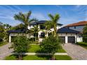 Beautiful two-story home with a black metal roof, white stucco, three-car garage and mature palm tree landscaping at 389 Bayview Ne Dr, St Petersburg, FL 33704