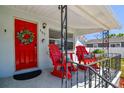 Inviting covered front porch with two red rocking chairs and a decorative wreath on the bright red front door at 503 N Macdill Ave, Tampa, FL 33609