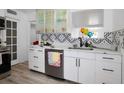 Modern kitchen featuring white cabinets, stainless steel appliances, and a unique backsplash at 559 Scotland St, Dunedin, FL 34698