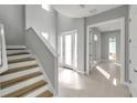 Bright foyer with wood and white staircase, complemented by neutral paint and tile floors at 6023 Cat Claw Ln, Bradenton, FL 34210