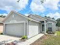 Home exterior featuring a two-car garage, walkway and manicured lawn at 6248 Tabogi Trl, Wesley Chapel, FL 33545