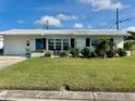 Charming single-story home with a well-manicured lawn, bright blue door, and white tile roof at 14019 89Th Ave, Seminole, FL 33776