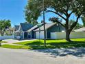 View of the home from across the street, landscaped lawn, and a white fence at 3000 Tangerine Ter, Palm Harbor, FL 34684