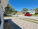 Quiet street view with brick paver driveway, blue recycling bin, and lush landscaping at 3000 Tangerine Ter, Palm Harbor, FL 34684