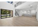 Bright open-concept living room with high ceilings, wood floors, modern staircase, and view to the kitchen at 3020 W Helen Ave, Tampa, FL 33611