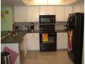 Well-lit kitchen with white cabinets, essential appliances, and tiled flooring at 4179 Juniper St, Port Charlotte, FL 33948