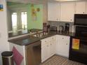 A functional kitchen with white cabinets, black appliances, and a stainless steel dishwasher at 4179 Juniper St, Port Charlotte, FL 33948