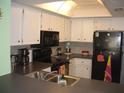 Efficient kitchen featuring white cabinetry, black appliances, and tile backsplash at 4179 Juniper St, Port Charlotte, FL 33948