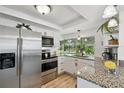 Bright kitchen featuring stainless steel appliances, granite countertops, white cabinetry, and a large window at 4240 Woodsville Dr, New Port Richey, FL 34652