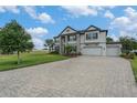 Elegant home boasts a three-car garage, landscaped front yard, and a spacious paved driveway, surrounded by greenery at 9843 Cabernet Ave, Seffner, FL 33584
