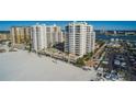 Aerial view of beachfront condos, a pool, and palm trees, with ocean views in the background at 11 San Marco St # 407, Clearwater Beach, FL 33767