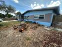 Single-story home featuring a brick exterior and landscaping, including cut tree branches on the lawn at 1105 Connecticut Rd, Tarpon Springs, FL 34689