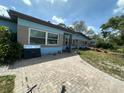 Single-story home with a brick and light blue exterior, surrounded by trees and greenery at 1105 Connecticut Rd, Tarpon Springs, FL 34689