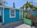 View of a cozy beach house with colorful exterior paint, lush palm trees, and a manicured yard at 126 119Th Ave, Treasure Island, FL 33706
