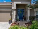 Inviting front entrance featuring decorative columns, a vibrant blue door, and seasonal decorations at 13302 Trailing Moss Dr, Dade City, FL 33525