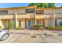 Beige two-story townhouse featuring a welcoming entrance, small garden, and convenient parking spaces at 1424 Highland Ridge Cir, Brandon, FL 33510
