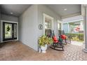 Cozy front porch featuring brick flooring, rocking chairs, and decorative potted plant at 19529 Lily Pond Ct, Brooksville, FL 34601